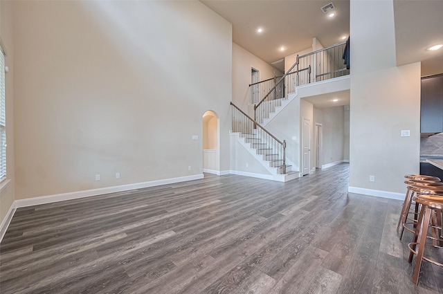 14538 Bending Maple Dr, Houston, TX 77069 - unfurnished living room with dark wood-style flooring, arched walkways, stairway, a high ceiling, and recessed lighting