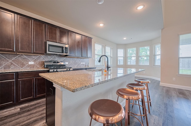 14538 Bending Maple Dr, Houston, TX 77069 - kitchen with appliances with stainless steel finishes, a breakfast bar area, decorative backsplash, light stone countertops, and dark wood-type flooring