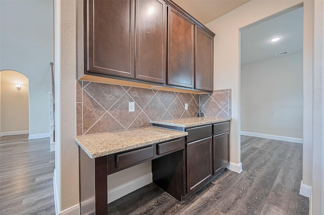 14538 Bending Maple Dr, Houston, TX 77069 - kitchen featuring arched walkways, dark wood-style floors, tasteful backsplash, and light stone countertops