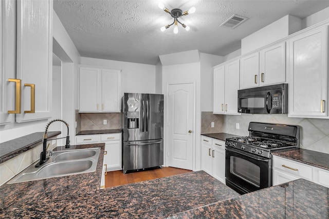 7402 Hollister Rdg, Houston, TX 77040 - kitchen with black appliances, a textured ceiling, wood finished floors, white cabinetry, and decorative backsplash