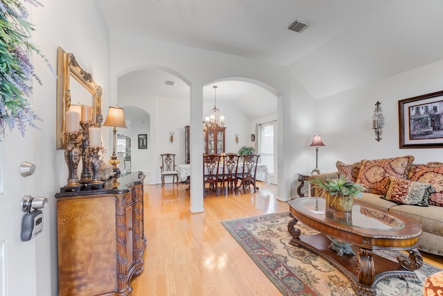 17906 Keenan Cv, Houston, TX 77084 - living area featuring arched walkways, vaulted ceiling, light wood-style flooring, and a chandelier