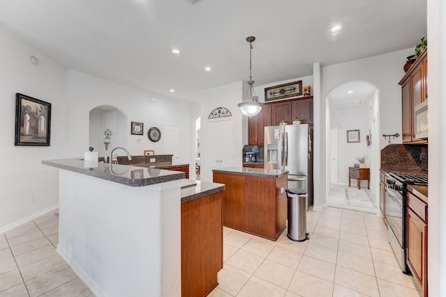 17906 Keenan Cv, Houston, TX 77084 - kitchen with a center island with sink, appliances with stainless steel finishes, arched walkways, light tile patterned floors, and recessed lighting
