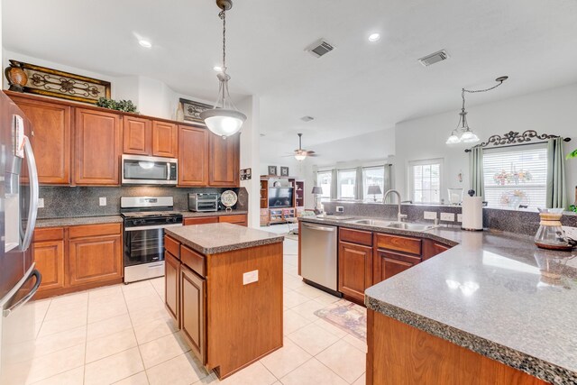 17906 Keenan Cv, Houston, TX 77084 - kitchen featuring stainless steel appliances, a spacious island, brown cabinets, and recessed lighting