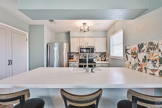 4023 Spanish Main Blvd, Galveston, TX 77554 - kitchen with stainless steel appliances, a breakfast bar area, light countertops, tasteful backsplash, and a peninsula