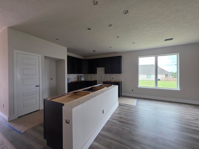 2035 Winepress Rd, Brenham, TX 77833 - kitchen featuring dark cabinets, wood finished floors, and a kitchen island