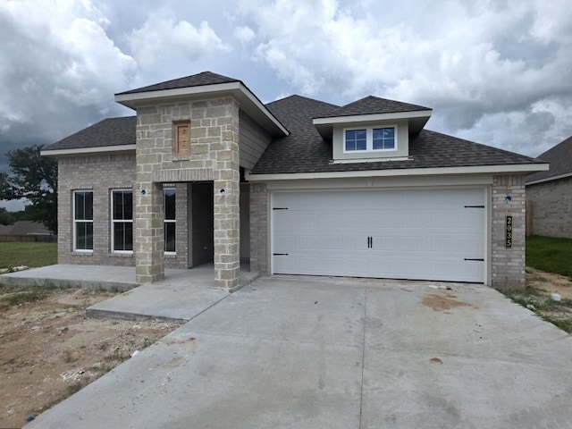 2035 Winepress Rd, Brenham, TX 77833 - view of front facade with driveway, a shingled roof, an attached garage, and stone siding