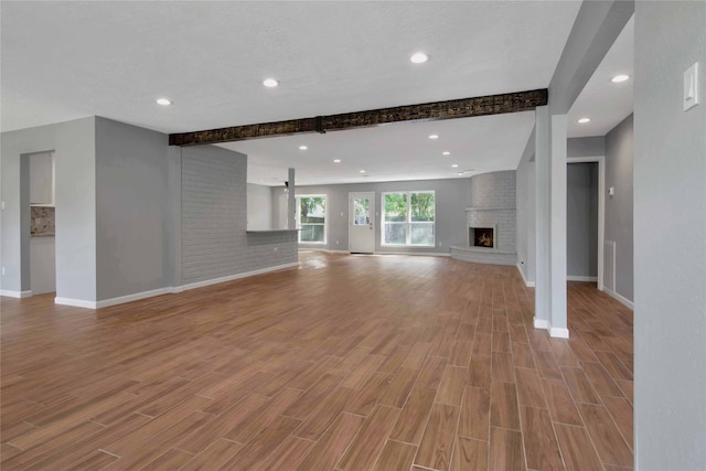 12811 Golden Tee Ln, Houston, TX 77099 - unfurnished living room featuring beam ceiling, wood finished floors, a brick fireplace, and recessed lighting