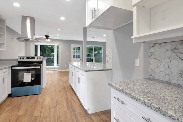 12811 Golden Tee Ln, Houston, TX 77099 - kitchen with electric range, island exhaust hood, ceiling fan, open shelves, and white cabinetry