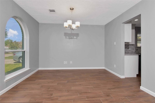 12811 Golden Tee Ln, Houston, TX 77099 - unfurnished dining area featuring a chandelier, wood finished floors, and a textured ceiling