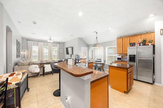 3015 Crescent Oaks Park Ln, Spring, TX 77386 - kitchen with stainless steel refrigerator with ice dispenser, a kitchen island with sink, arched walkways, light tile patterned floors, and a kitchen bar