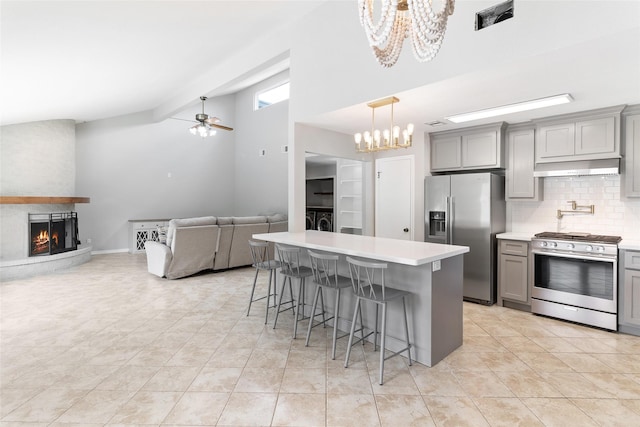 500 E Main St, Clute, TX 77531 - kitchen with stainless steel appliances, gray cabinetry, a chandelier, under cabinet range hood, and high vaulted ceiling
