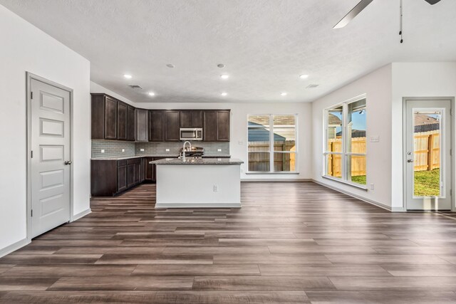 1418 Lake Ridge Dr, Brenham, TX 77833 - kitchen featuring stainless steel microwave, dark wood-type flooring, recessed lighting, dark brown cabinets, and decorative backsplash