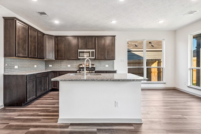 1418 Lake Ridge Dr, Brenham, TX 77833 - kitchen with stainless steel microwave, dark wood-style floors, light stone countertops, dark brown cabinets, and recessed lighting