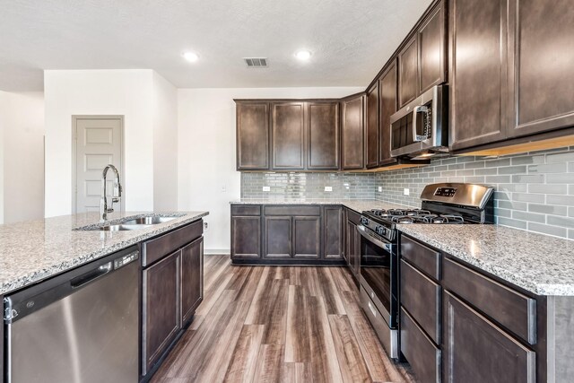 1418 Lake Ridge Dr, Brenham, TX 77833 - kitchen with appliances with stainless steel finishes, dark wood-style floors, dark brown cabinets, light stone countertops, and recessed lighting