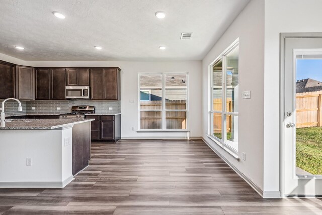 1418 Lake Ridge Dr, Brenham, TX 77833 - kitchen with stainless steel microwave, stove, dark brown cabinets, stone countertops, and dark wood-style flooring
