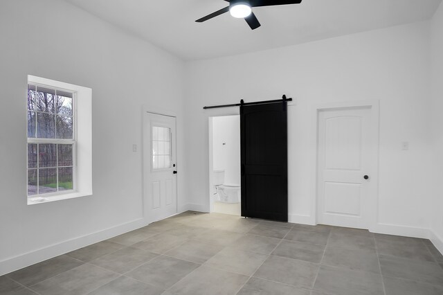 17128 Spindle Oaks Dr, Conroe, TX 77385 - unfurnished room with a barn door, ceiling fan, and light tile patterned floors
