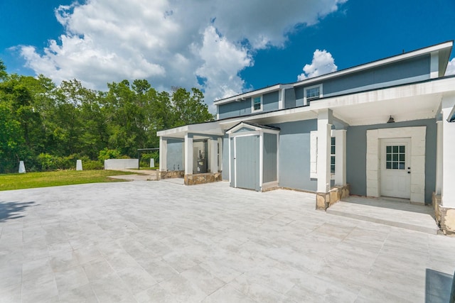 17128 Spindle Oaks Dr, Conroe, TX 77385 - rear view of property featuring stucco siding, a patio area, and a storage unit