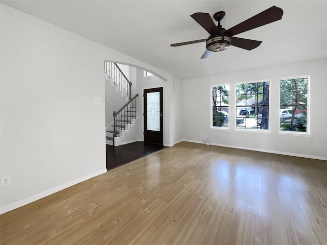 7007 Madison Trl, Houston, TX 77084 - unfurnished living room featuring stairs, arched walkways, ceiling fan, and wood finished floors