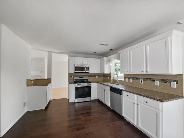 7007 Madison Trl, Houston, TX 77084 - kitchen featuring stainless steel appliances, dark wood-style flooring, white cabinets, decorative backsplash, and decorative light fixtures