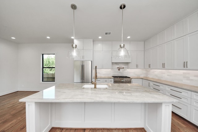 4541 Walker St, Houston, TX 77023 - kitchen featuring premium appliances, decorative backsplash, white cabinetry, dark wood-type flooring, and recessed lighting