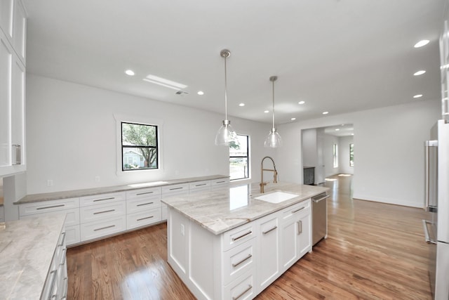 4541 Walker St, Houston, TX 77023 - kitchen featuring stainless steel appliances, white cabinets, recessed lighting, light wood-style flooring, and light stone countertops