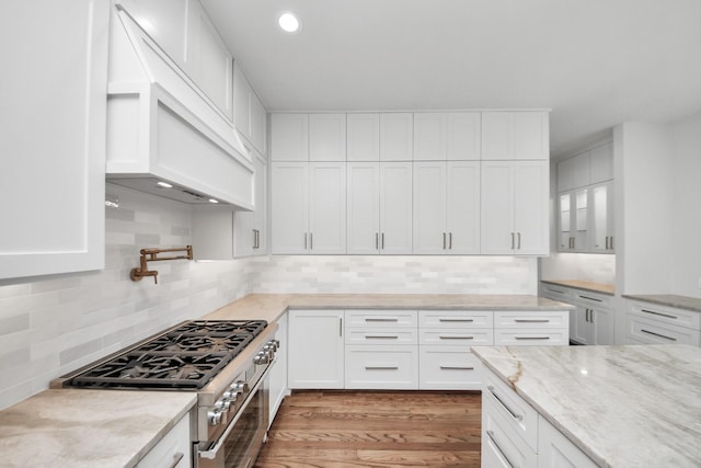 4541 Walker St, Houston, TX 77023 - kitchen with gas range, exhaust hood, white cabinetry, and recessed lighting