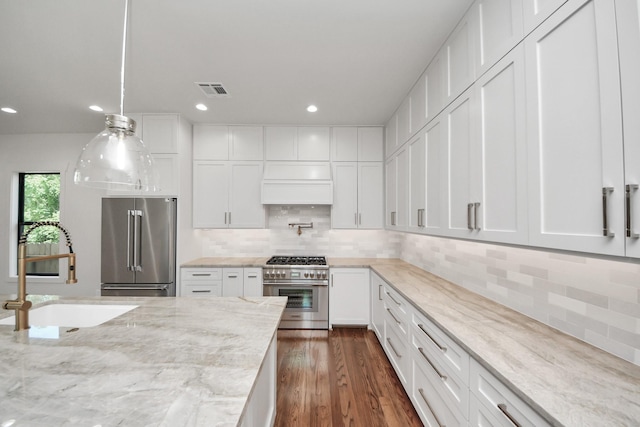 4541 Walker St, Houston, TX 77023 - kitchen with high end appliances, white cabinetry, pendant lighting, recessed lighting, and dark wood finished floors