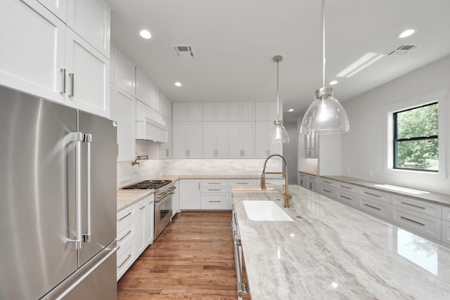 4541 Walker St, Houston, TX 77023 - kitchen with high end appliances, premium range hood, recessed lighting, white cabinetry, and tasteful backsplash