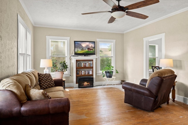 213 E Feagin St, Livingston, TX 77351 - living area featuring wood-type flooring, a ceiling fan, a warm lit fireplace, crown molding, and a textured ceiling