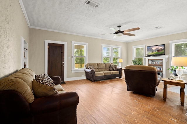 213 E Feagin St, Livingston, TX 77351 - living area featuring light wood-type flooring, healthy amount of natural light, a ceiling fan, a textured wall, and ornamental molding