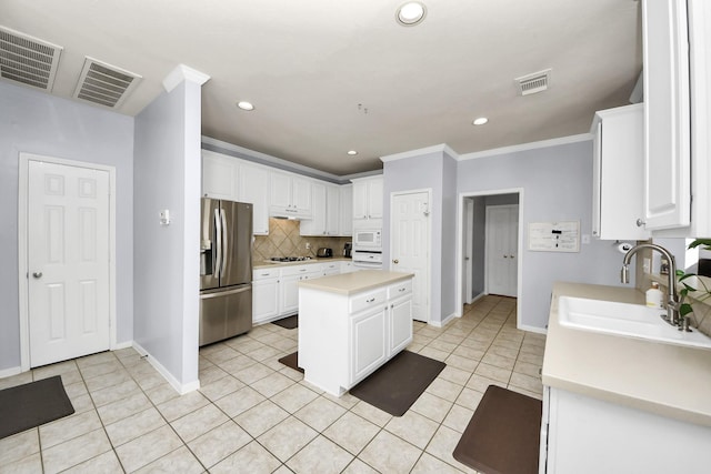 2613 Broussard Ct, Seabrook, TX 77586 - kitchen with stainless steel fridge, gas stovetop, decorative backsplash, light tile patterned floors, and ornamental molding