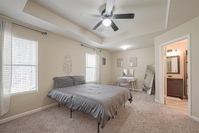 2335 Village Leaf Dr, Spring, TX 77386 - bedroom with a tray ceiling, light carpet, ceiling fan, and connected bathroom