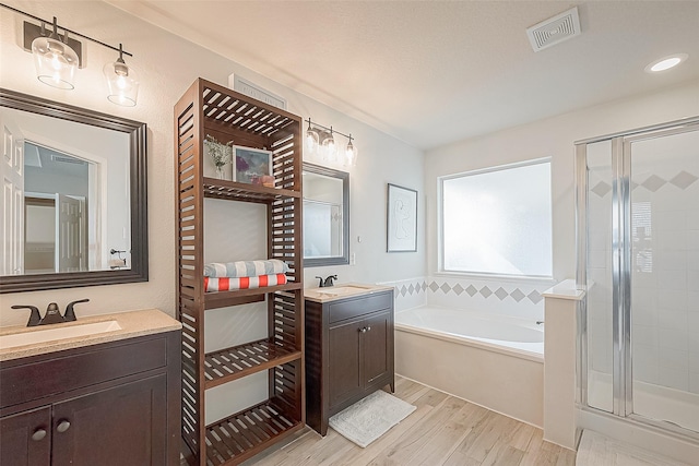 2335 Village Leaf Dr, Spring, TX 77386 - bathroom featuring wood finished floors, a garden tub, two vanities, and a stall shower