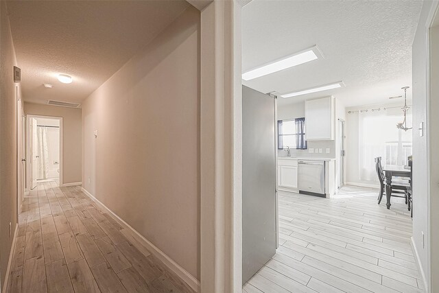 2335 Village Leaf Dr, Spring, TX 77386 - corridor with a textured ceiling and light wood finished floors