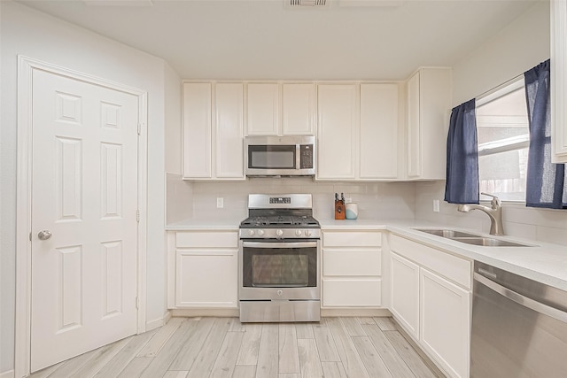 2335 Village Leaf Dr, Spring, TX 77386 - kitchen featuring stainless steel appliances, light wood-type flooring, white cabinetry, and light countertops