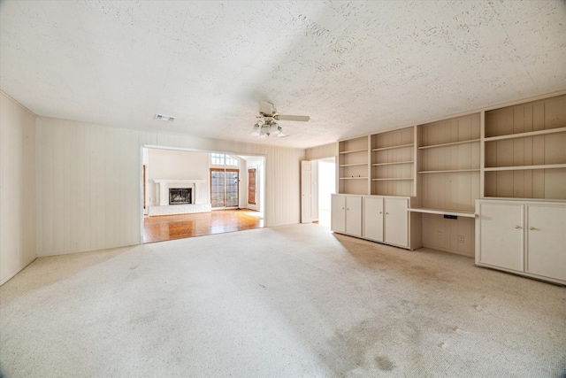 7525 Middlewood St, Houston, TX 77063 - unfurnished living room with a ceiling fan, carpet floors, a fireplace with raised hearth, a textured ceiling, and wooden walls