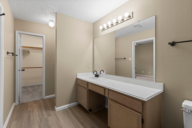 29222 Waltham St, Spring, TX 77386 - bathroom with wood finished floors, vanity, a spacious closet, and a textured ceiling