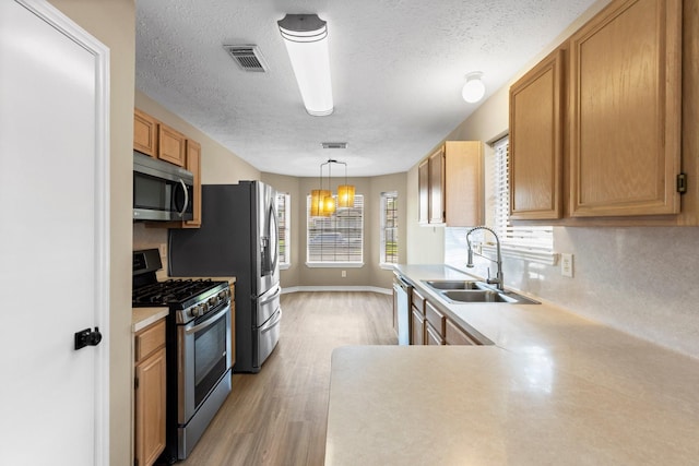 29222 Waltham St, Spring, TX 77386 - kitchen featuring appliances with stainless steel finishes, light wood-style floors, light countertops, a textured ceiling, and backsplash
