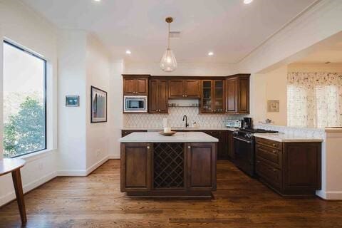 1616 Southmore Blvd, Houston, TX 77004 - kitchen featuring appliances with stainless steel finishes, light countertops, backsplash, dark wood finished floors, and glass insert cabinets