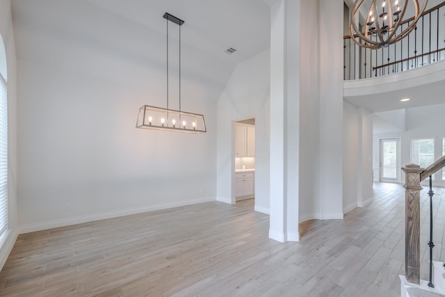 17010 Harpers Way, Conroe, TX 77385 - spare room with a chandelier, light wood finished floors, high vaulted ceiling, and stairway