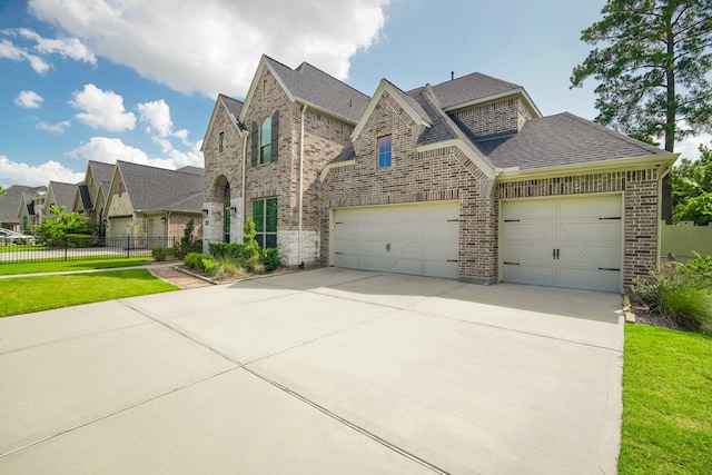 17010 Harpers Way, Conroe, TX 77385 - french country inspired facade with brick siding, concrete driveway, a shingled roof, and a garage