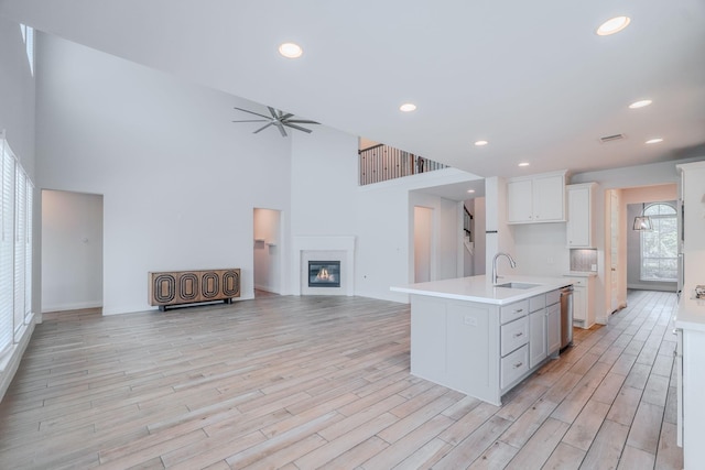 17010 Harpers Way, Conroe, TX 77385 - kitchen with open floor plan, light countertops, a glass covered fireplace, light wood-type flooring, and a ceiling fan