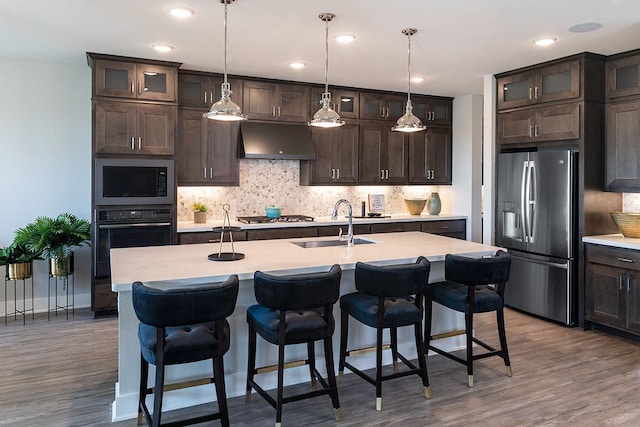 9218 Heckenberg Arbor Ln, Cypress, TX 77433 - kitchen featuring stainless steel appliances, exhaust hood, dark brown cabinets, tasteful backsplash, and recessed lighting