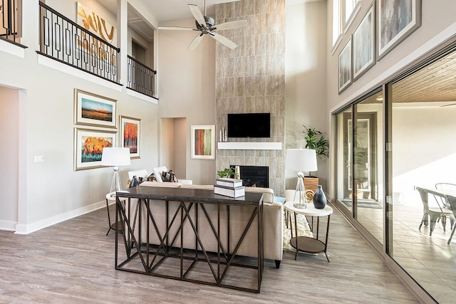 9218 Heckenberg Arbor Ln, Cypress, TX 77433 - living area featuring a towering ceiling, ceiling fan, a tiled fireplace, and wood finished floors