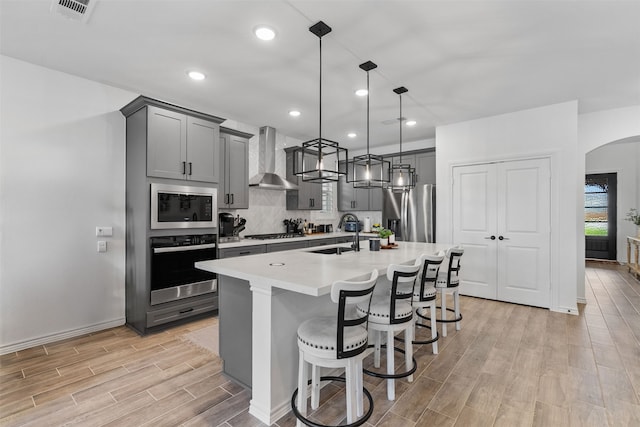 1224 Garden Jade Dr, Katy, TX 77493 - kitchen featuring appliances with stainless steel finishes, wall chimney range hood, gray cabinets, light wood-style flooring, and recessed lighting