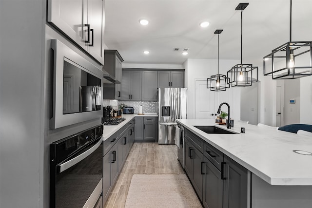 1224 Garden Jade Dr, Katy, TX 77493 - kitchen with stainless steel appliances, gray cabinets, light wood-style floors, backsplash, and a spacious island