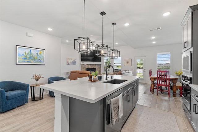 1224 Garden Jade Dr, Katy, TX 77493 - kitchen featuring appliances with stainless steel finishes, open floor plan, a fireplace, light countertops, and light wood-style flooring