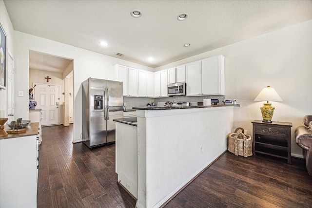 18314 Harvest Star Ct, Houston, TX 77084 - kitchen featuring appliances with stainless steel finishes, dark countertops, dark wood-style floors, white cabinets, and tasteful backsplash