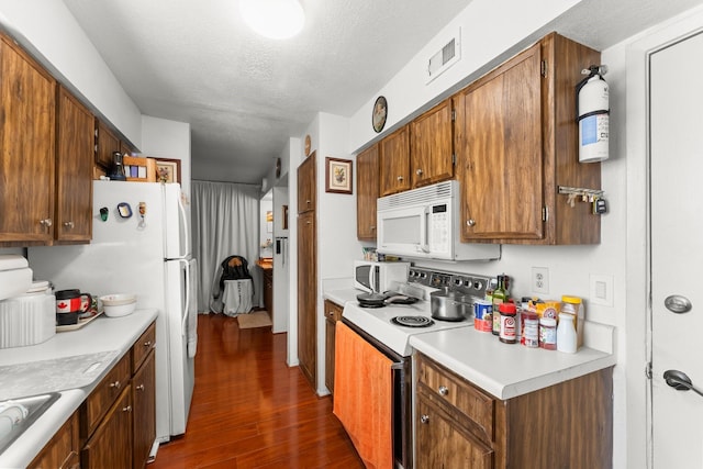 6701 Sands Point Dr Unit 114, Houston, TX 77074 - kitchen with white appliances, dark wood-style flooring, light countertops, a textured ceiling, and brown cabinetry