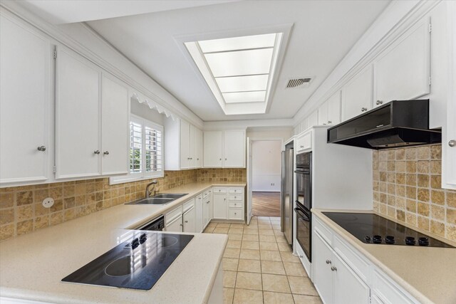 4932 Post Oak Timber Dr, Houston, TX 77056 - kitchen featuring black appliances, under cabinet range hood, white cabinetry, light tile patterned floors, and decorative backsplash